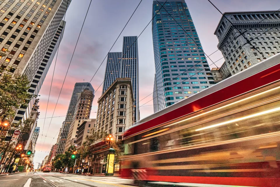 Blurred red San Francisco streetcar speeding past tall downtown buildings